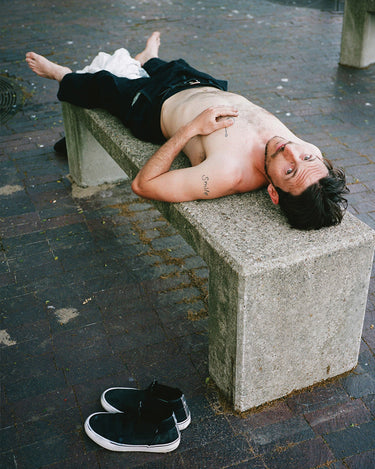Lifestyle shot of model laying on a street bench 